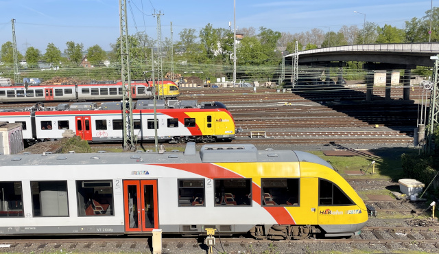 drei unterschiedliche Fahrzeuge mit gelb-rot-grauer Lackierung auf dem Gleisvorfeld